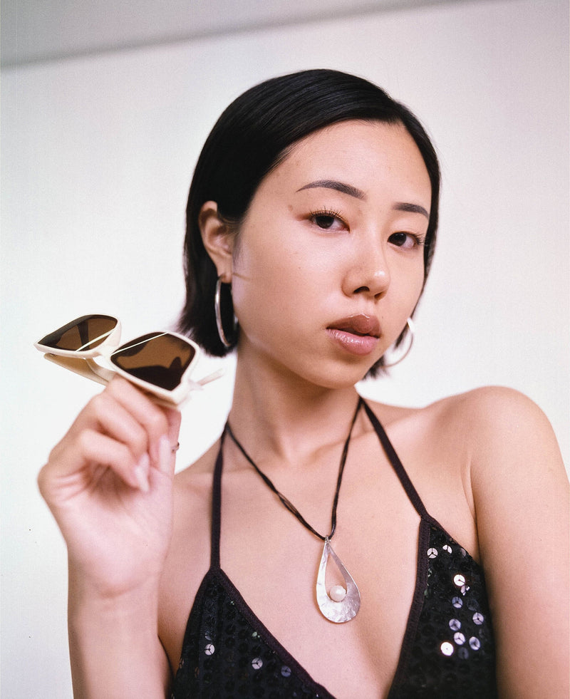 Hand holding a white and black 35mm camera against sunny blue California skies.