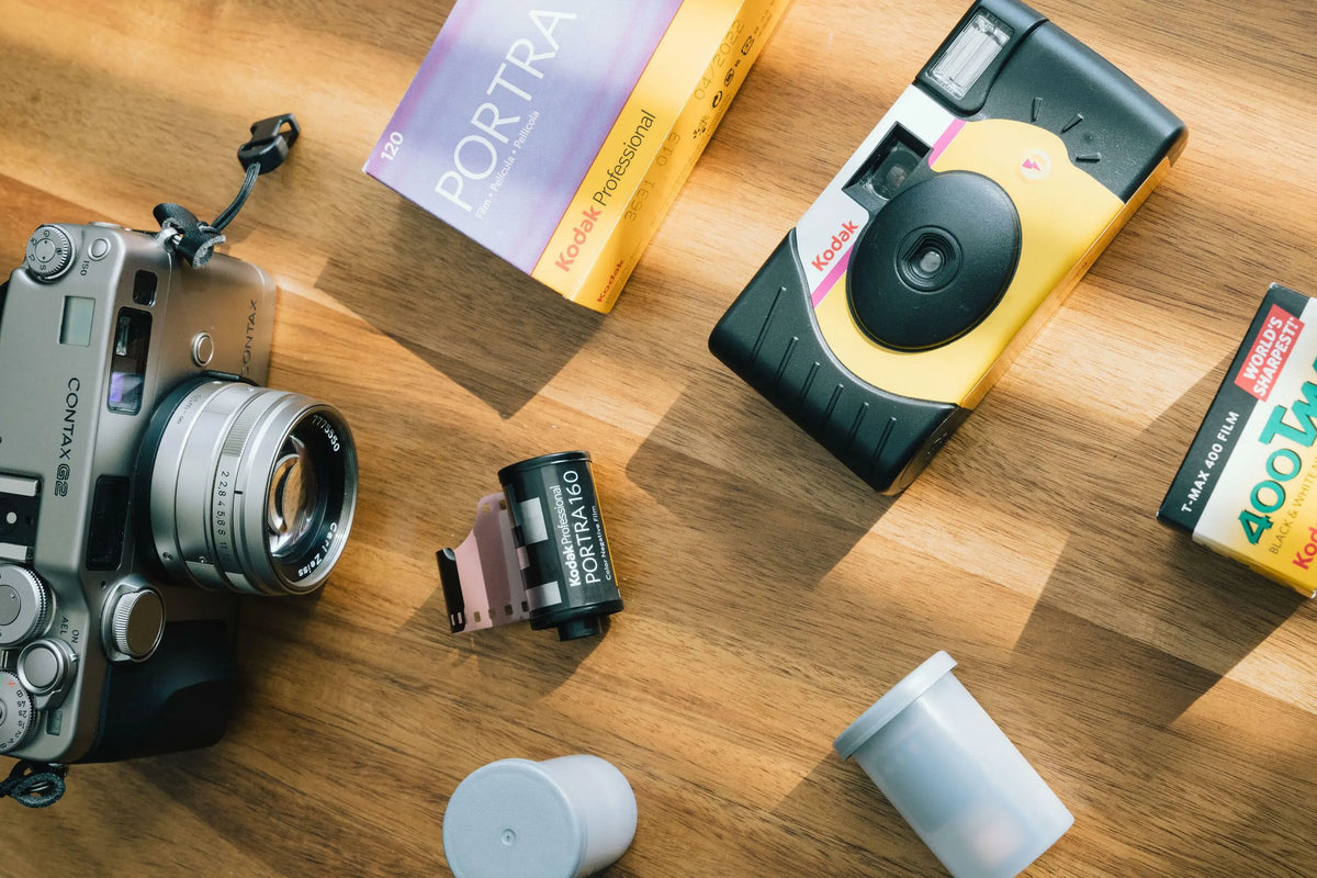 Hand holding a white and black 35mm camera against sunny blue California skies.