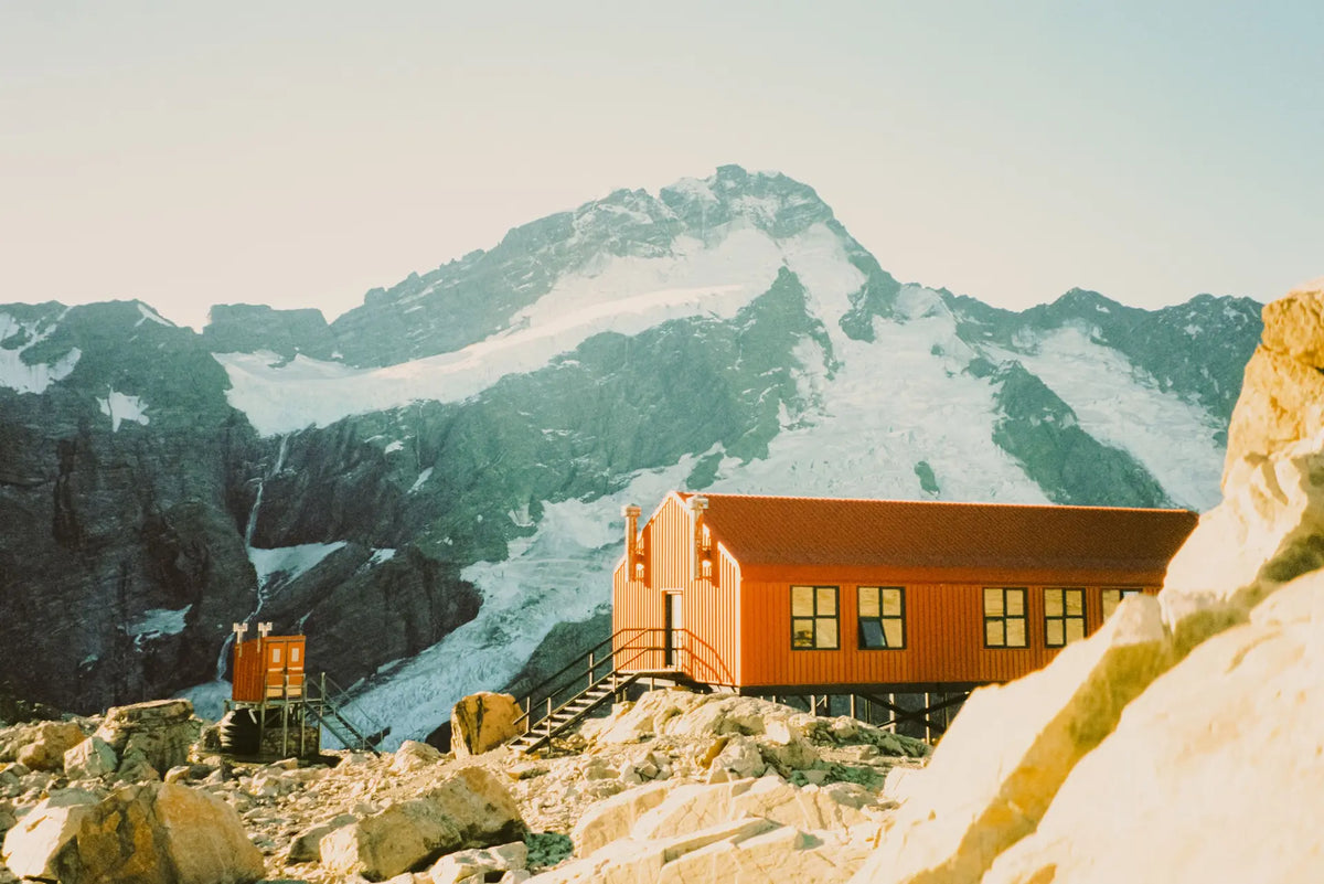 Hand holding a white and black 35mm camera against sunny blue California skies.