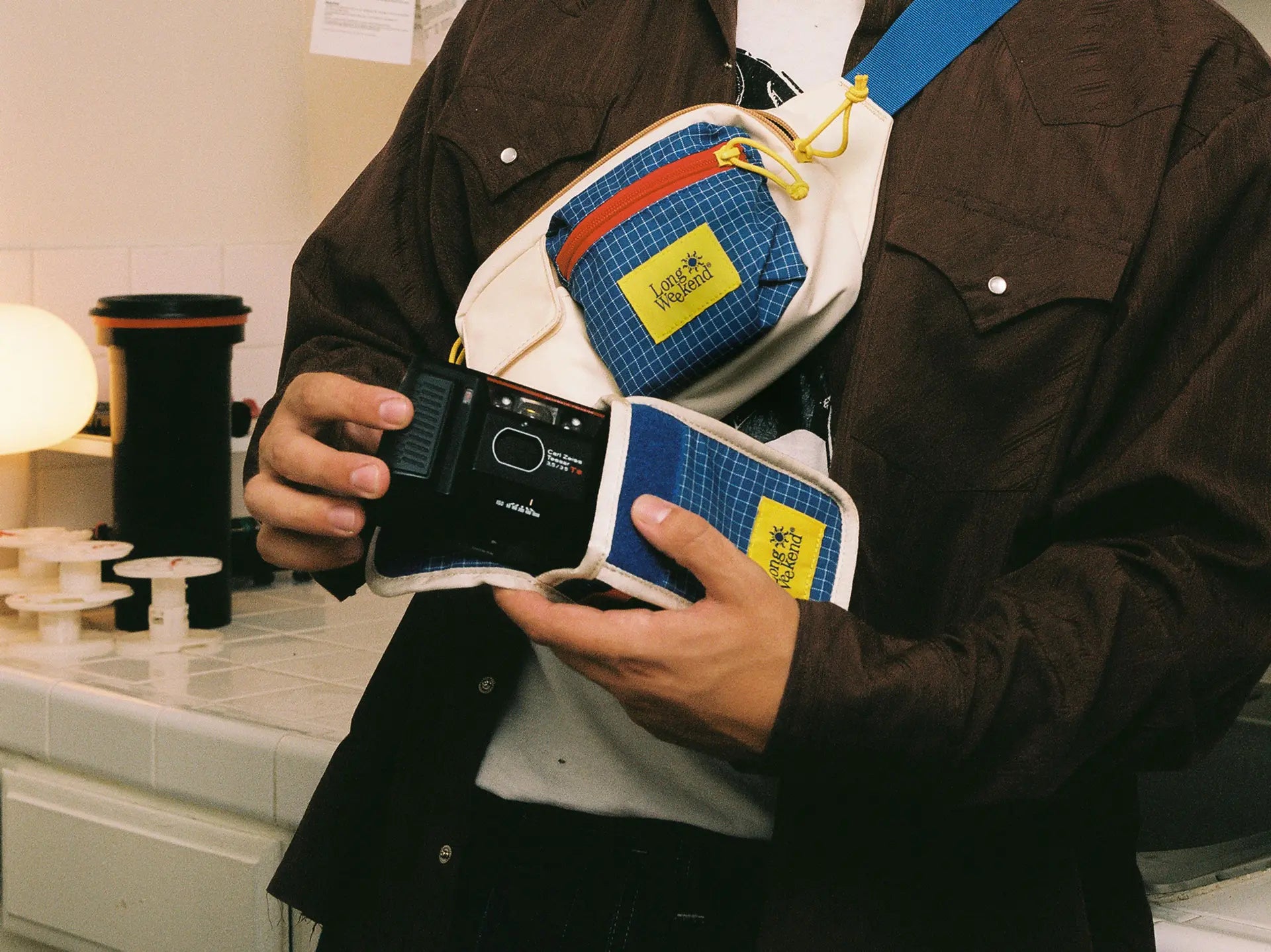 Man holding a 35mm film camera and creme pouch.