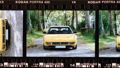 Hand holding a white and black 35mm camera against sunny blue California skies.