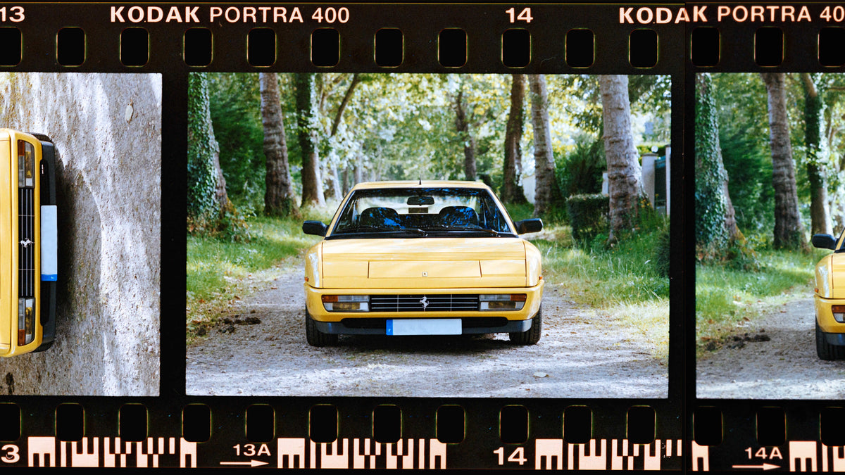 Hand holding a white and black 35mm camera against sunny blue California skies.